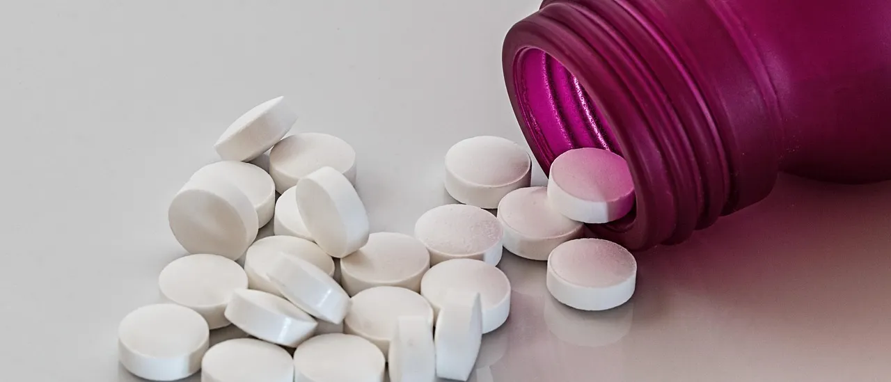 Prescription medication tablets spilling out of a bottle